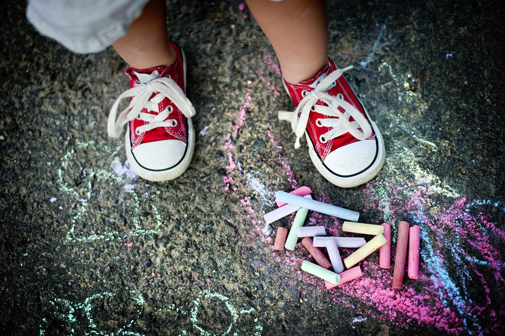 A toddler wearing sneakers outside on concrete