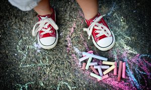 A toddler wearing sneakers outside on concrete