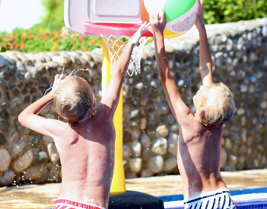 two tween boys playing water basketball