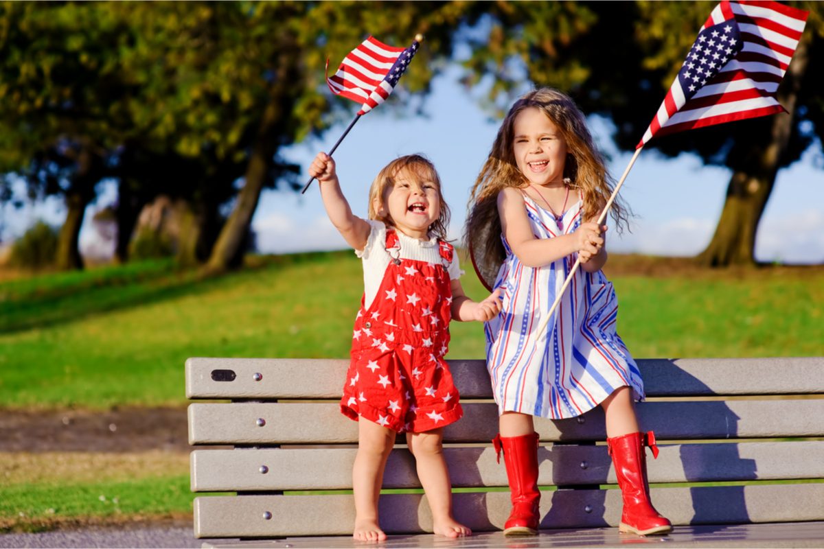 Two little girls waving U.S. flags at Memorial Day parade