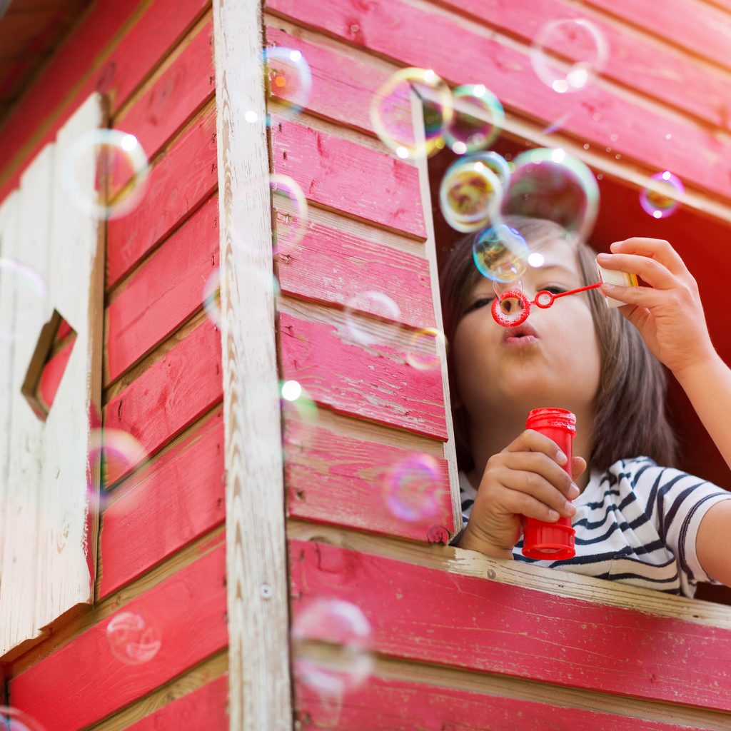Child blowing bubbles in a playhouse