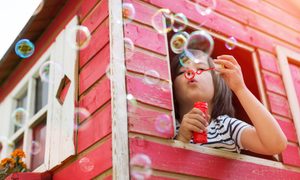 Child blowing bubbles in a playhouse