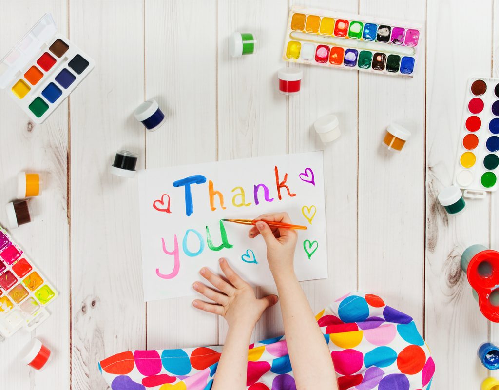 Child painting a thank you card to show gratitude