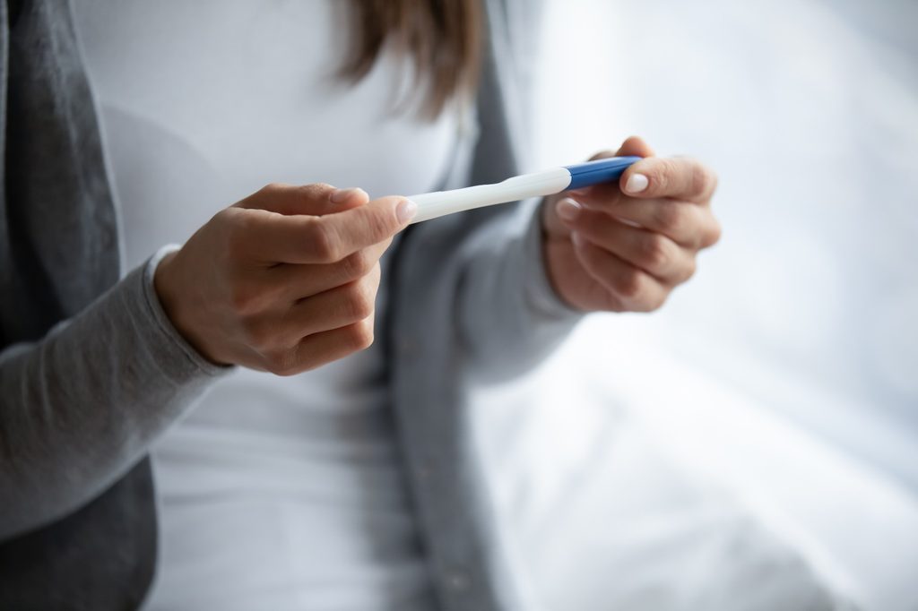 Woman holding a pregnancy test.