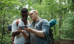 Two men looking at a smartphone in the woods