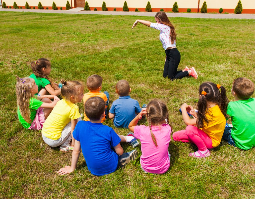 group of kids outside playing an improv game with an adult