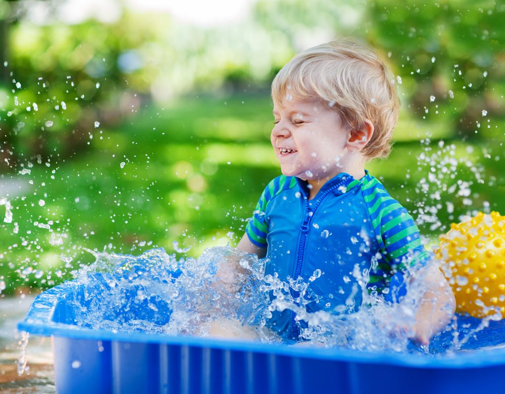 Toddler boy playing in kiddie pool