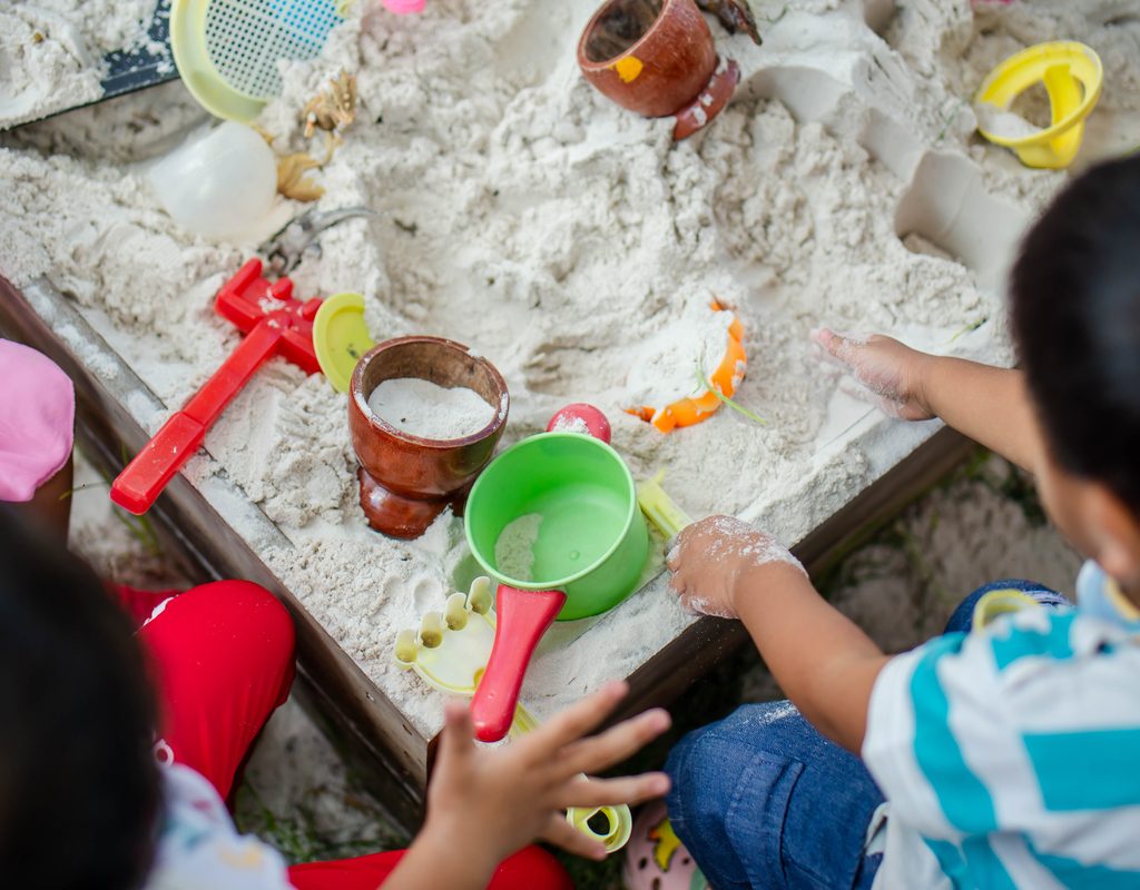 Toddlers playing in sand at summer birthday party