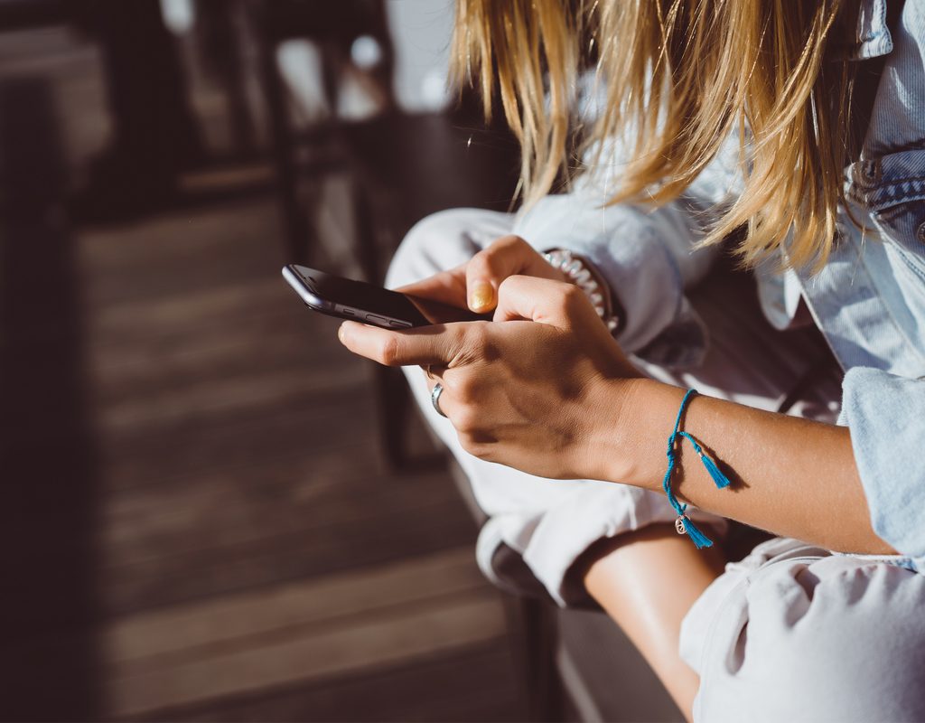 Young woman having fun on her iPhone outside on a sunny day
