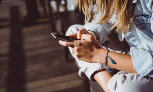 Young woman in a chair using her iPhone