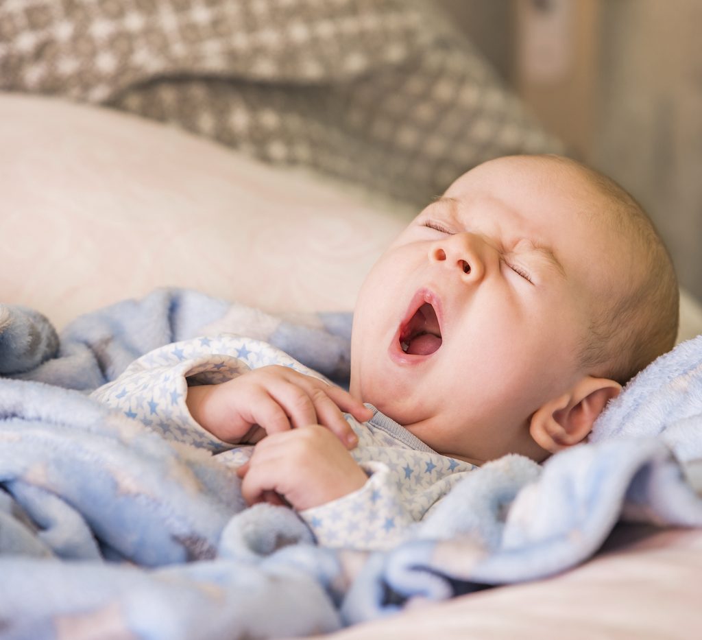 Baby wrapped in a blanket yawning