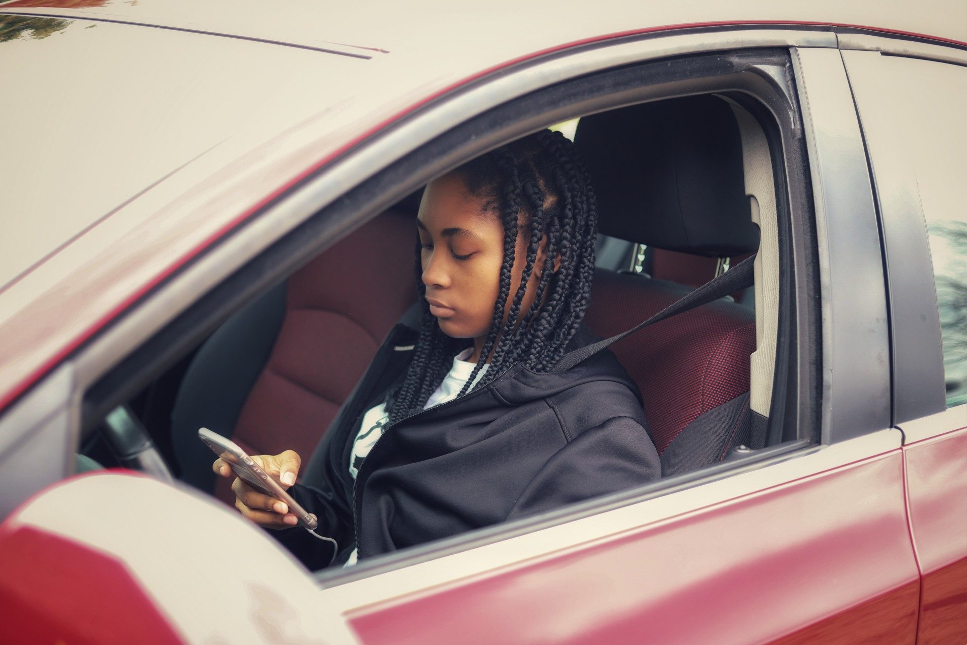 teen on her phone in the drivers seat of a car