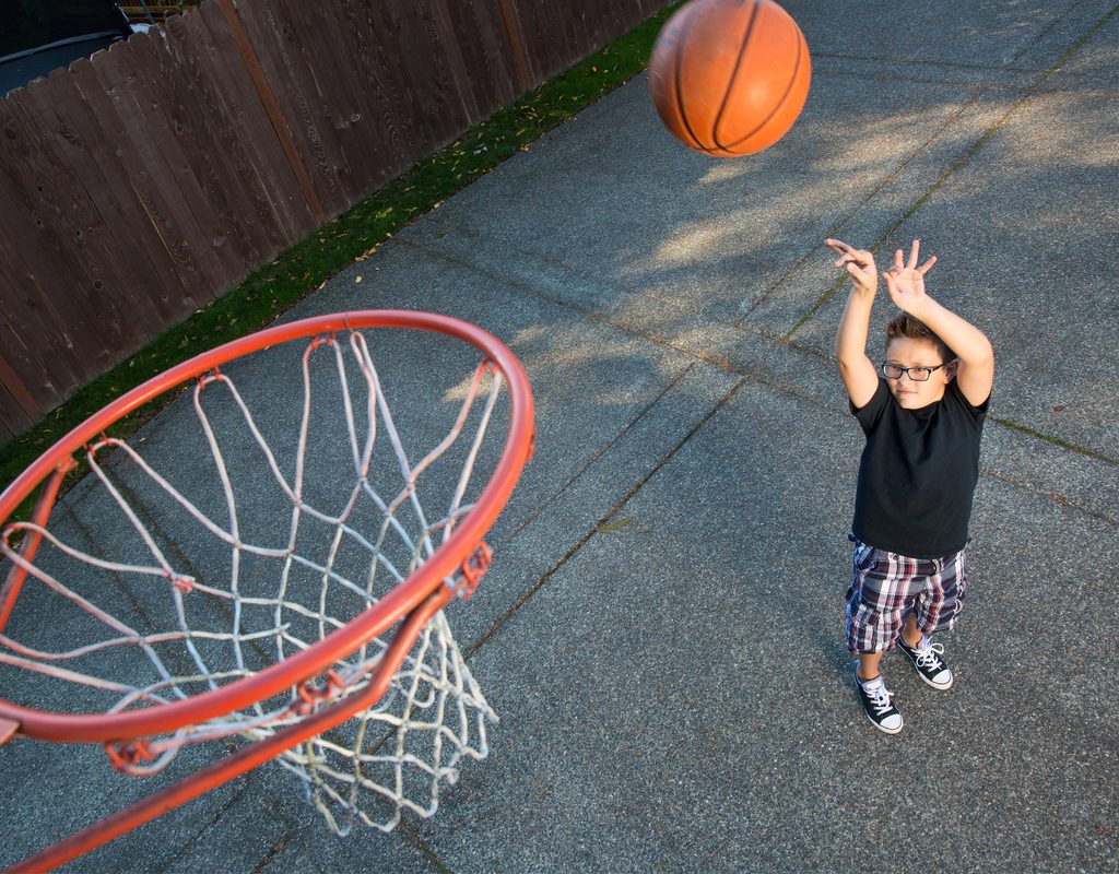 Boy shooting baskets in his backyard
