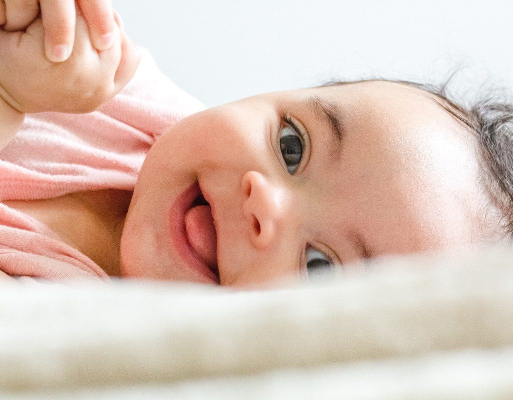 happy baby smiling with hands clasped