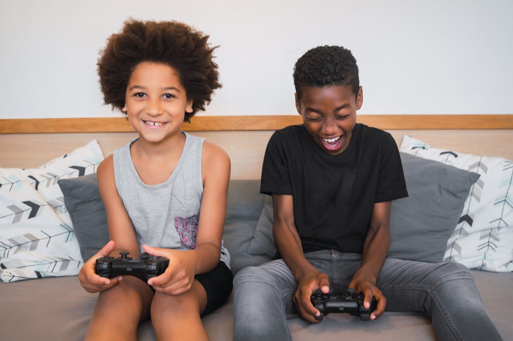 Two kids having fun playing video games on the couch