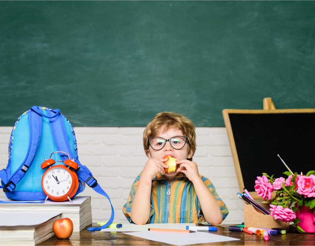Kindergarten boy eating an apple as a snack