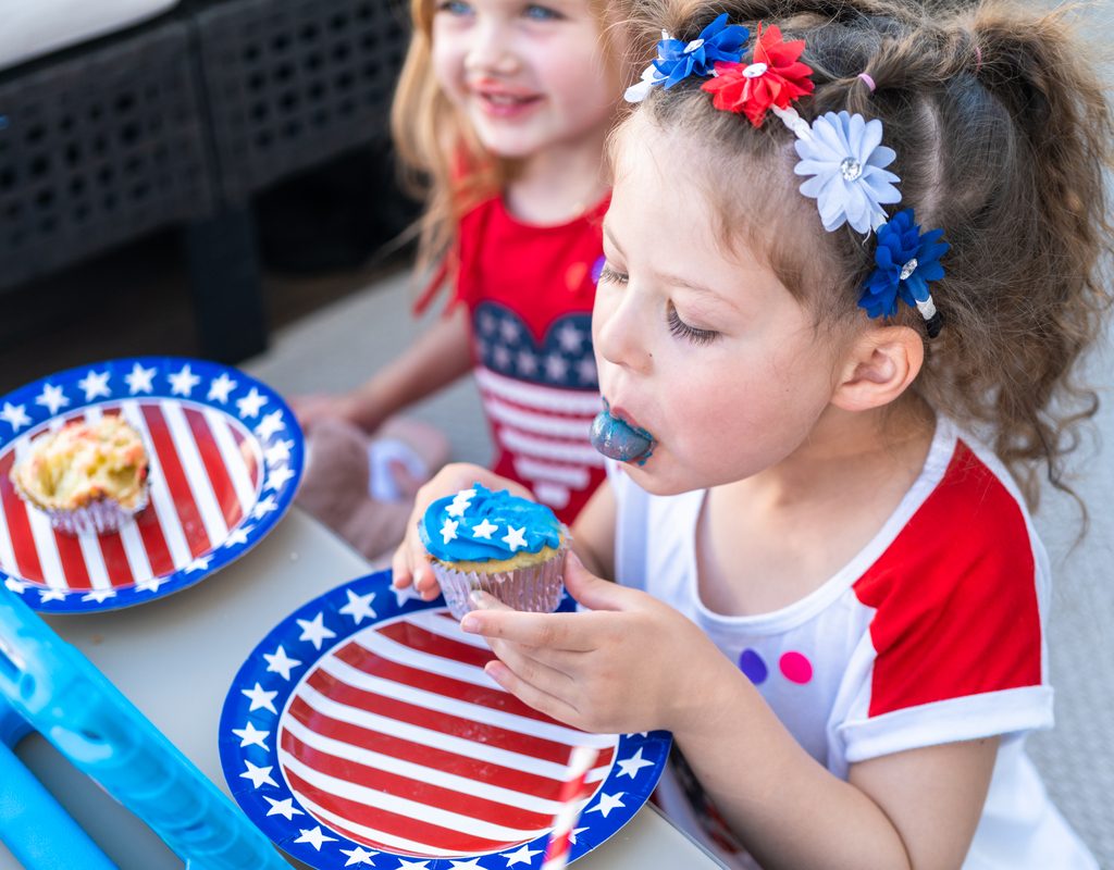 Two cute little girls eating cupcakes on the Fourth of July