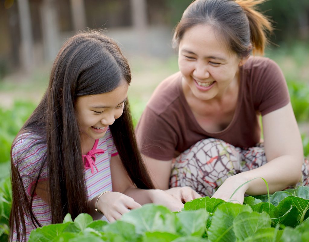mom and daughter tending to vegetables in garden