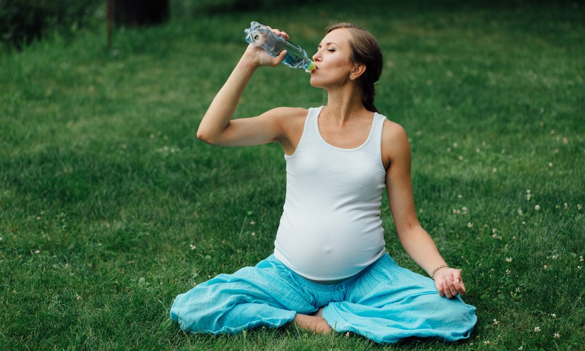 Pregnant woman drinking a bottle of water