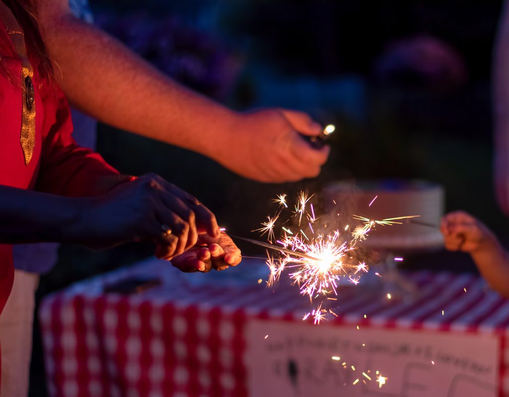 Woman lighting a sparkler on Fourth of July