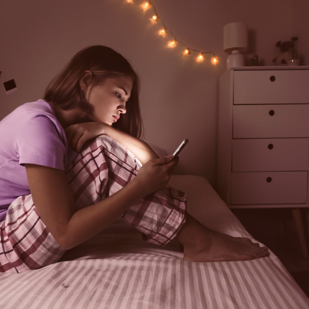 A teenage girl by herself on her cell phone.