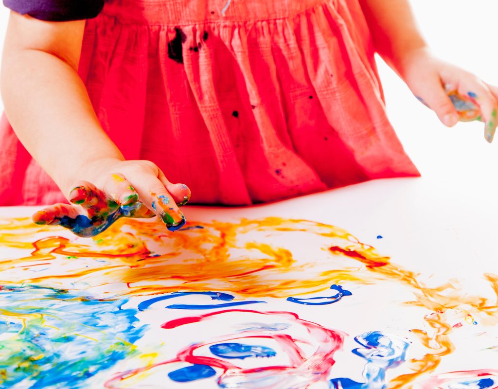 toddler girl having fun playing with finger paint