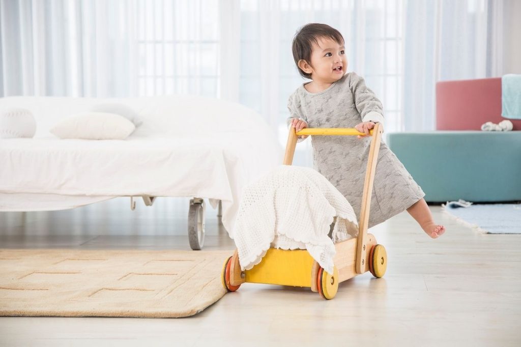 cute toddler pushing a baby walker