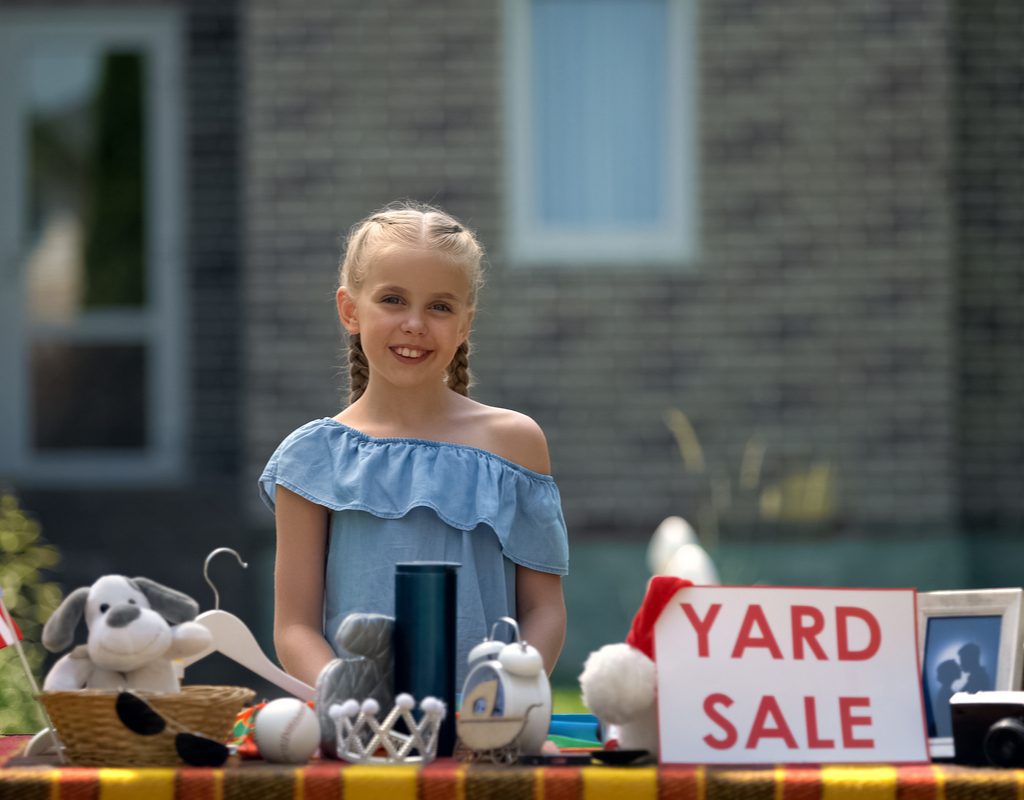 young girl selling her old toys at a garage sale