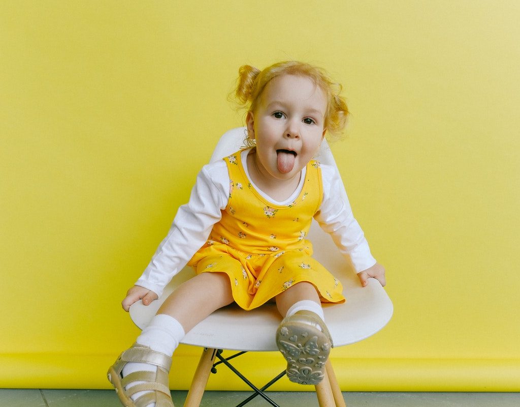 little girl sitting and sticking tongue out