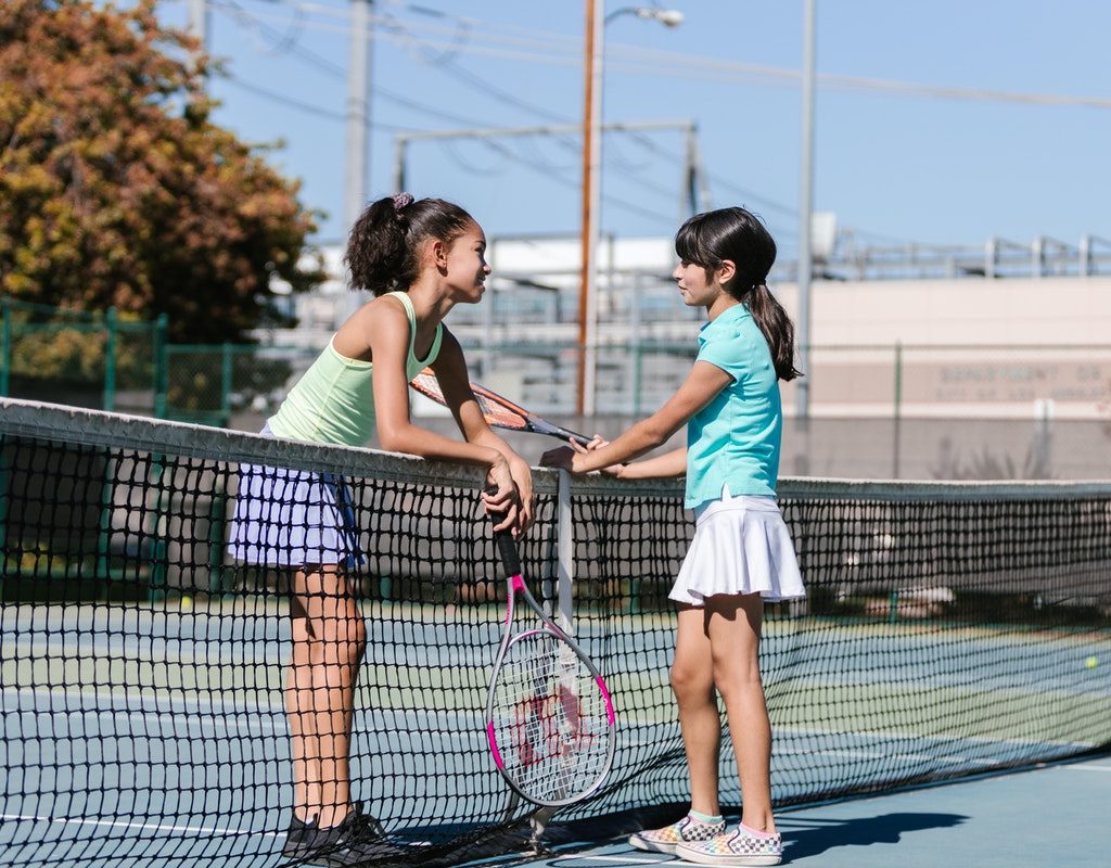 girls talking at a tennis court