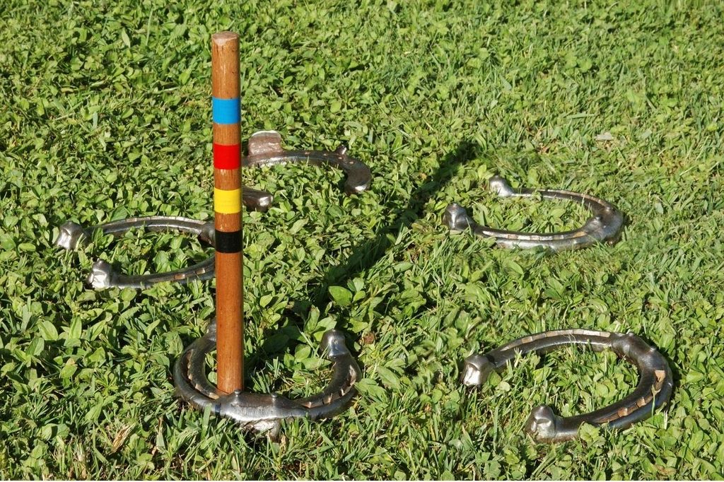 A game of horseshoes set up outside in the grass.