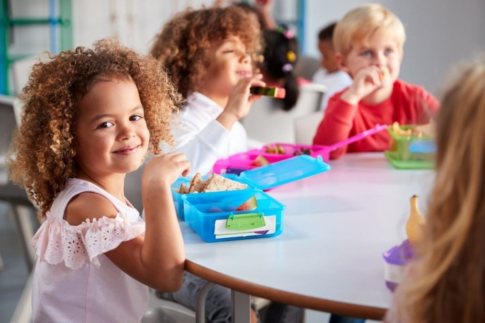 Group of kids at a table in school eating lunch.
