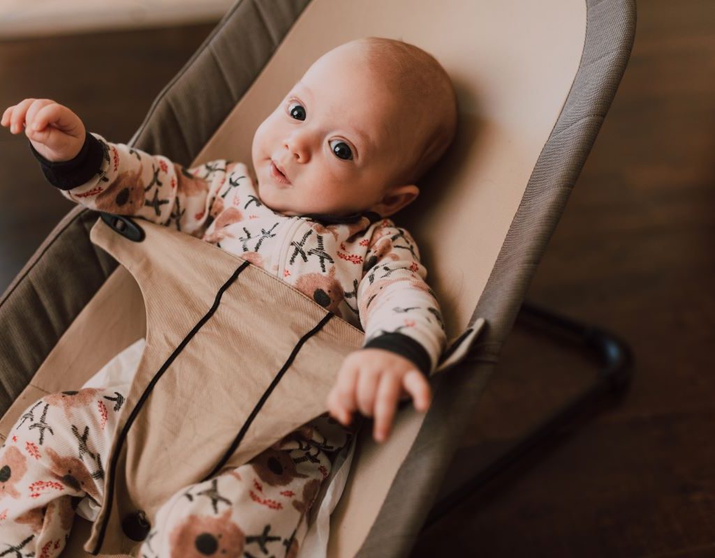 baby wearing sleeper in a bouncer