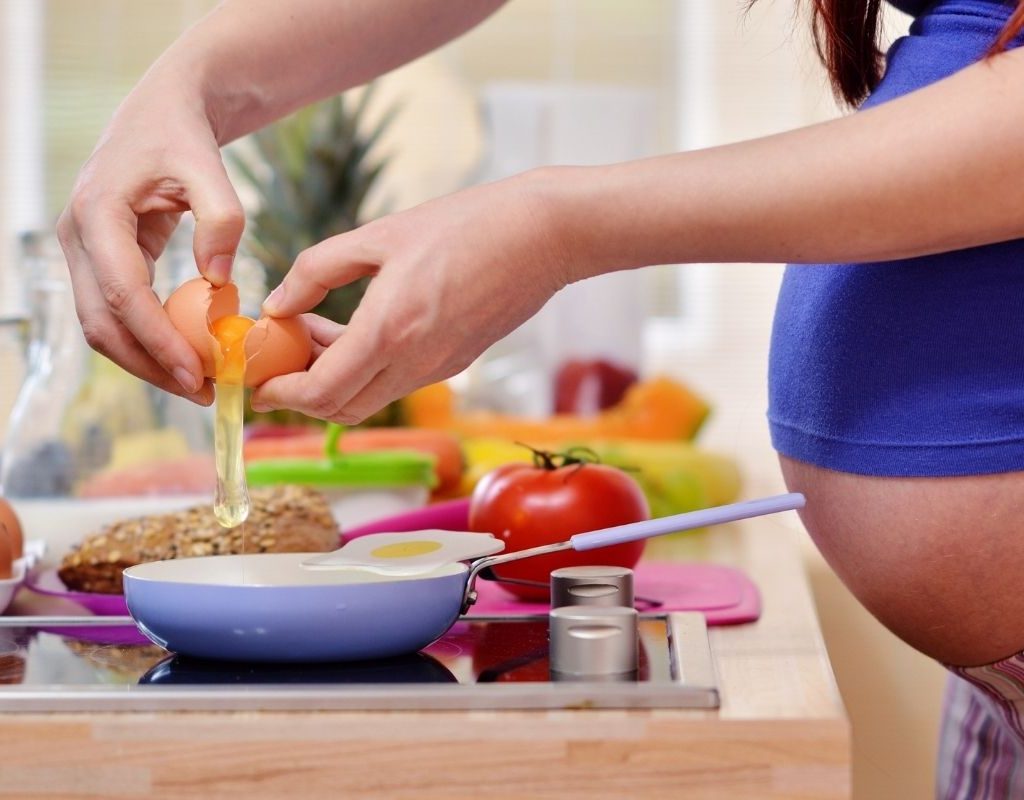 Pregnant woman making eggs.