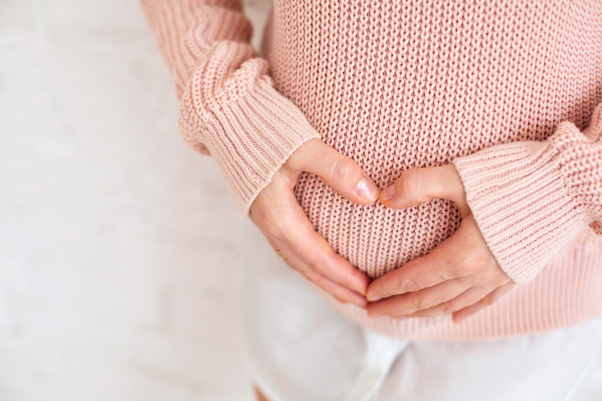 Woman making a heart with hands over Post partum belly