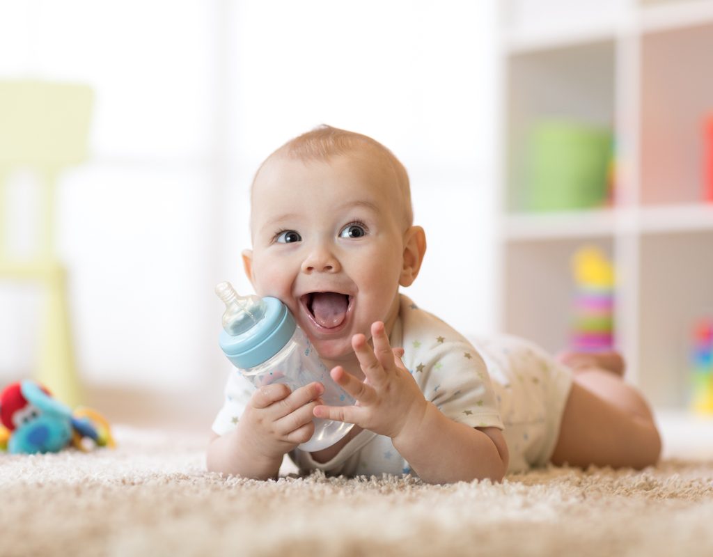 A baby holding a bottle.