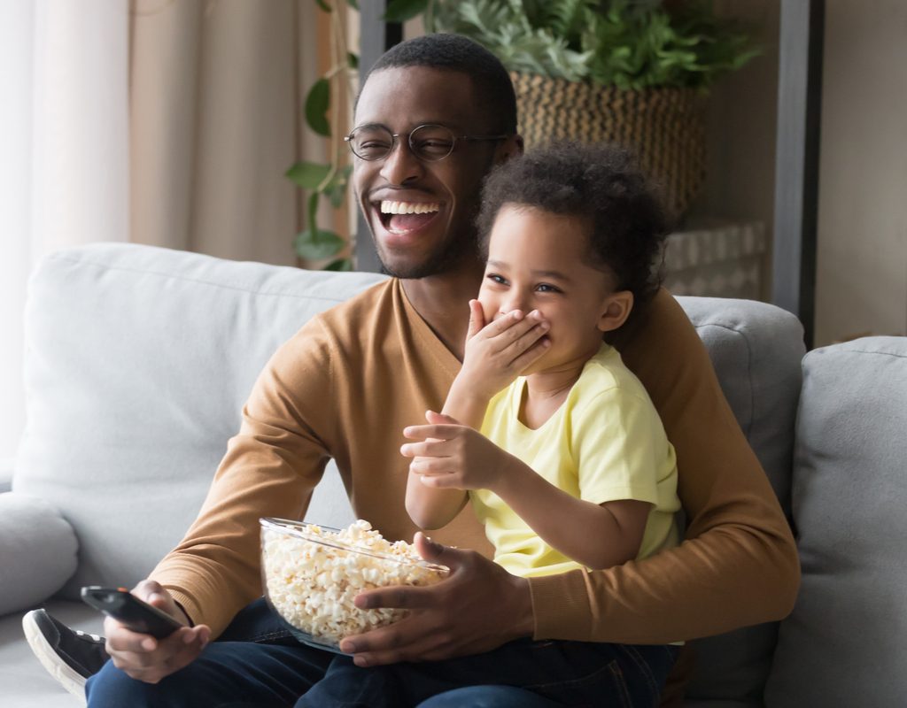 A family laughing while watching a movie.