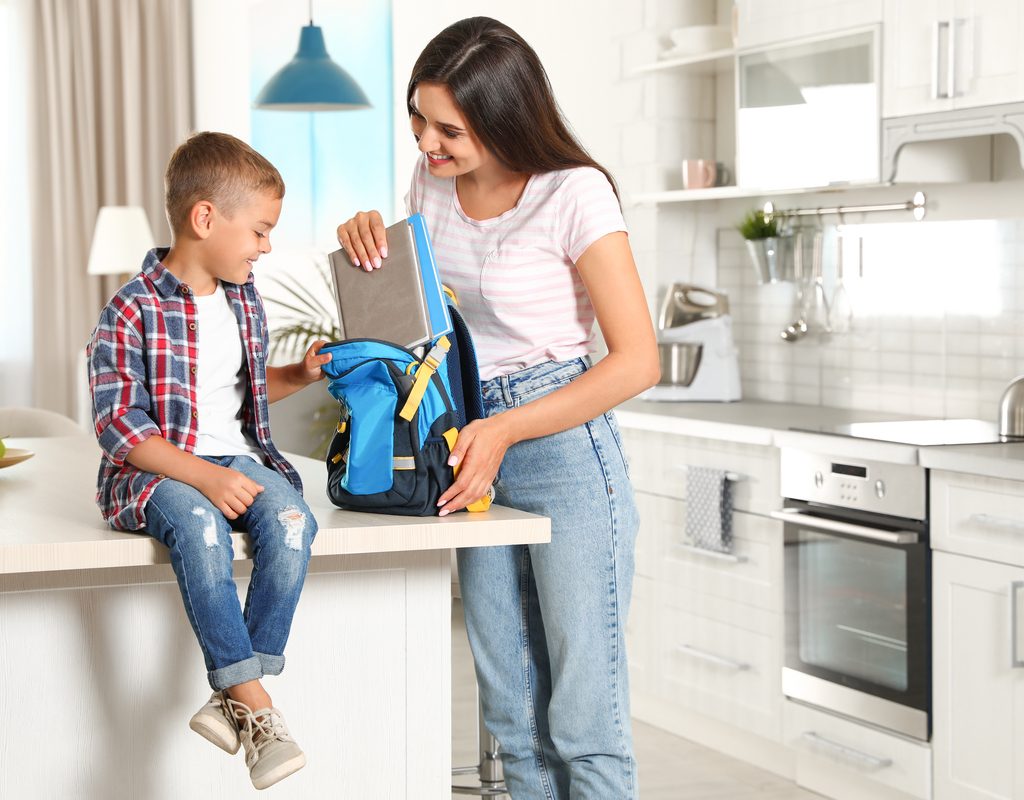 A mom and son getting his backpack ready for school.