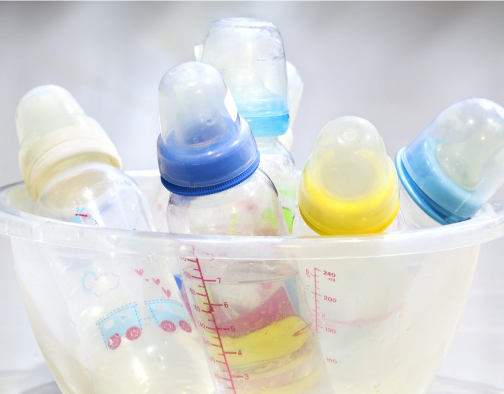 A cluster of different baby bottles in a bowl.
