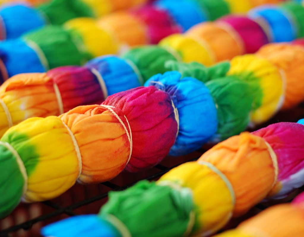 Tie-dye shirts with rubber bands waiting to be rinsed.