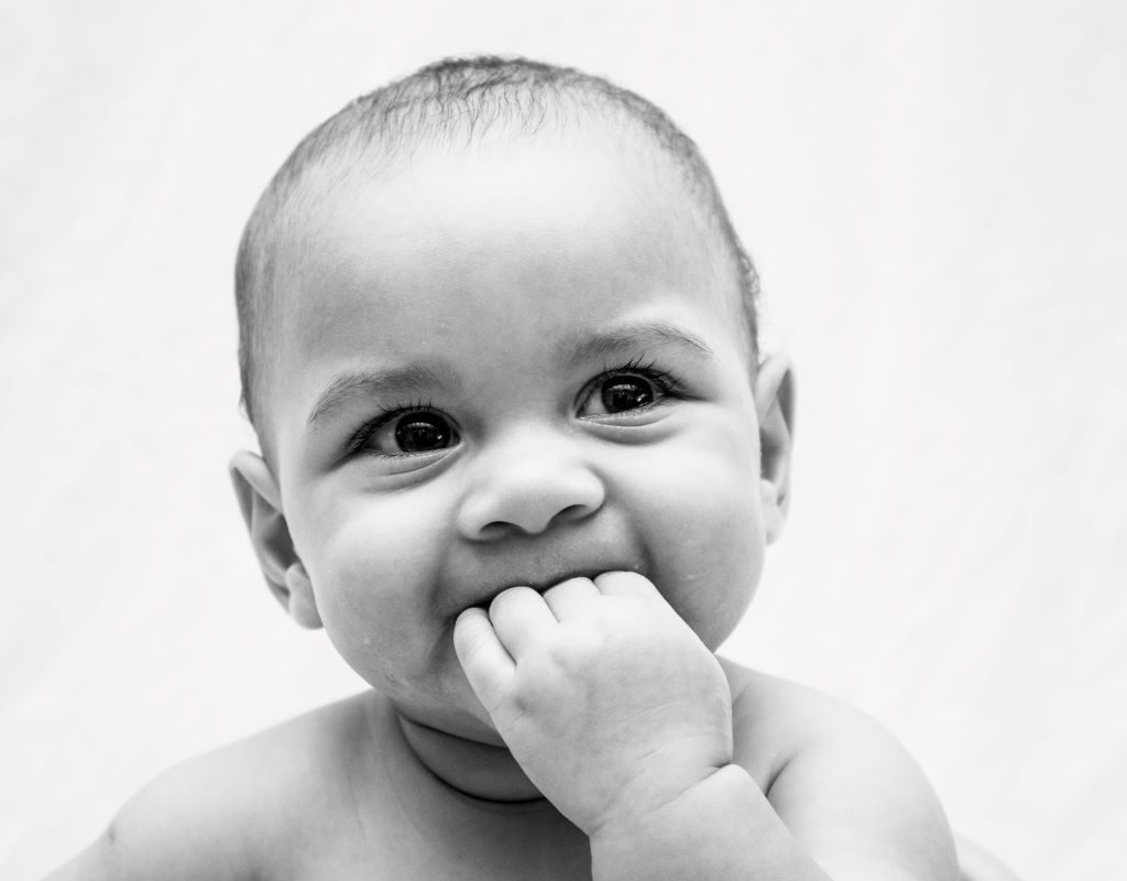 baby chewing on fingers and smiling