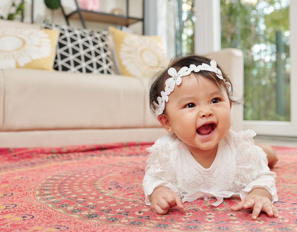 adorable baby playing on the floor in a white headband