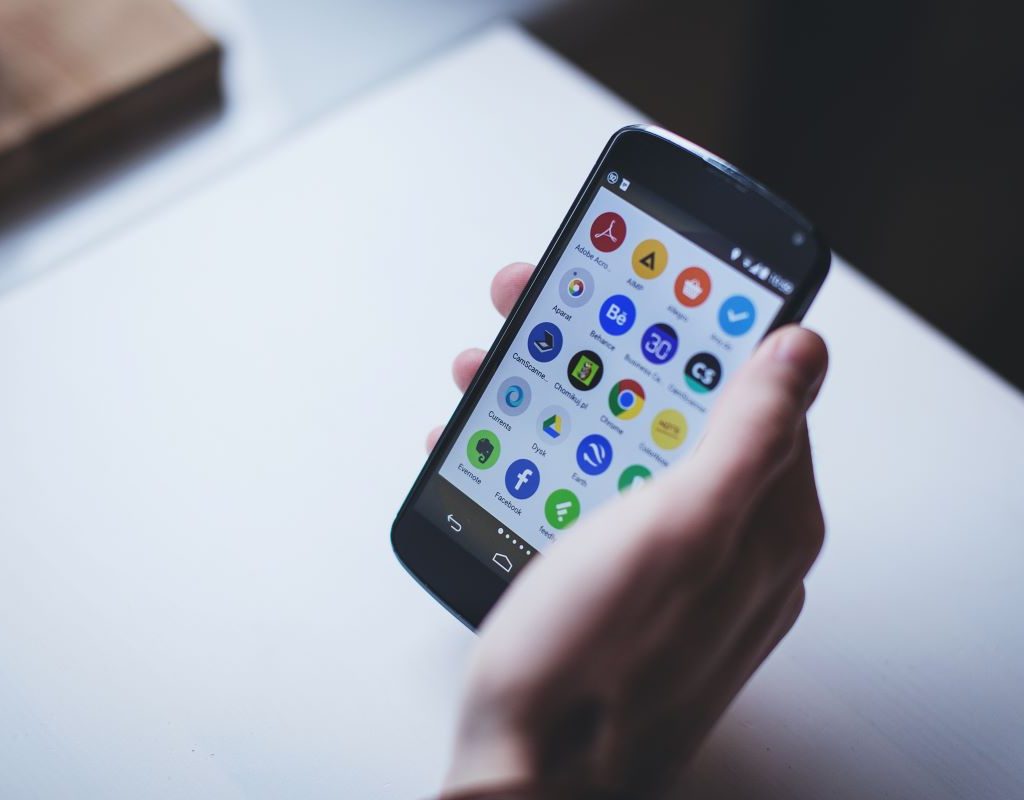 person holding a cellphone with apps