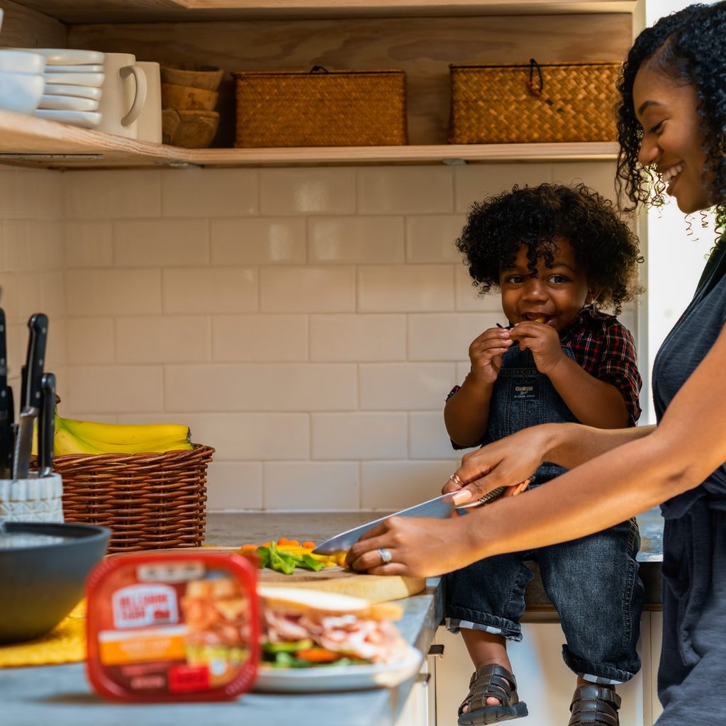 Mom cutting vegetables while child watches