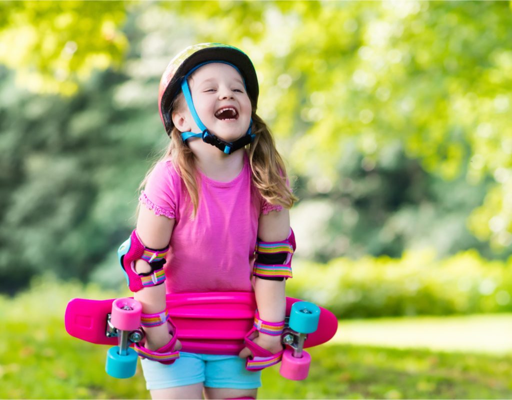 happy girl learning to ride a skateboard