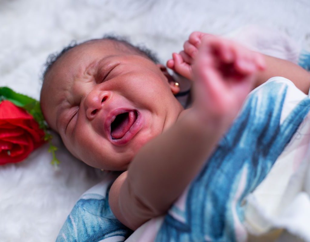 Newborn wrapped in a blanket and crying
