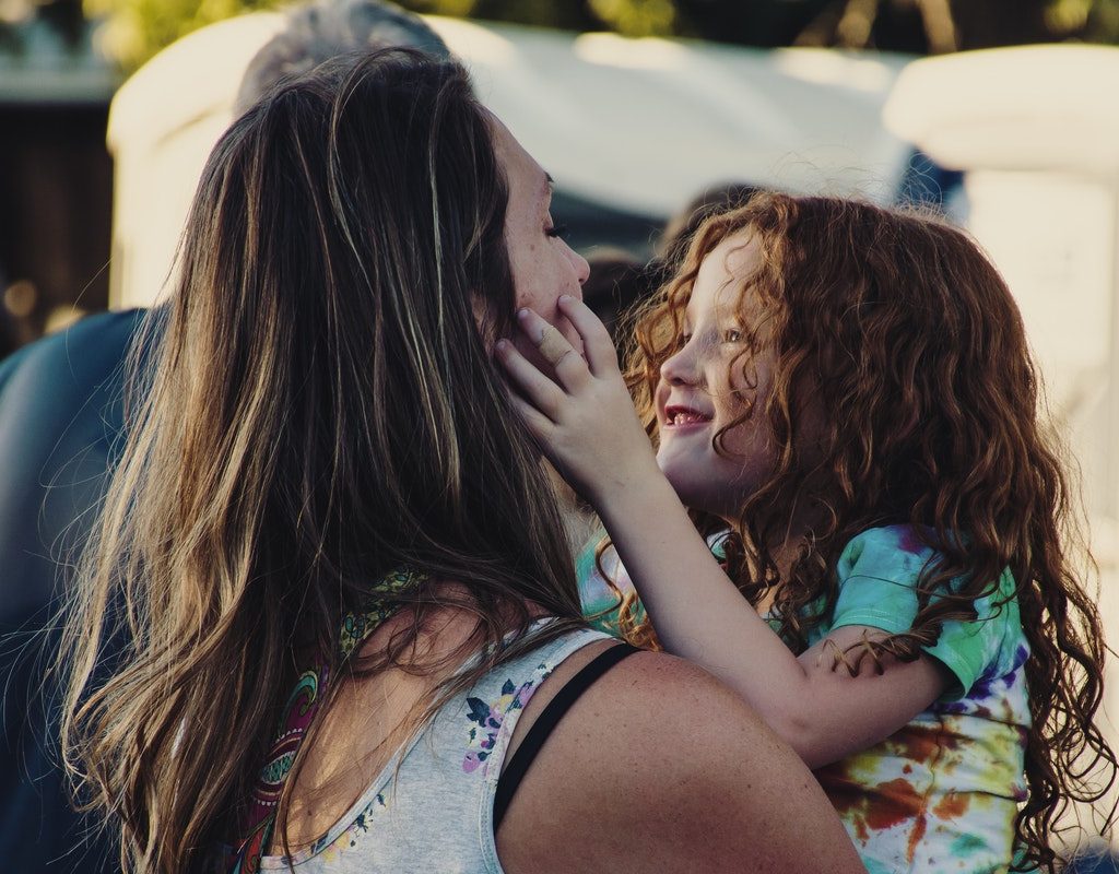 A mom holding her daughter while at a festival.