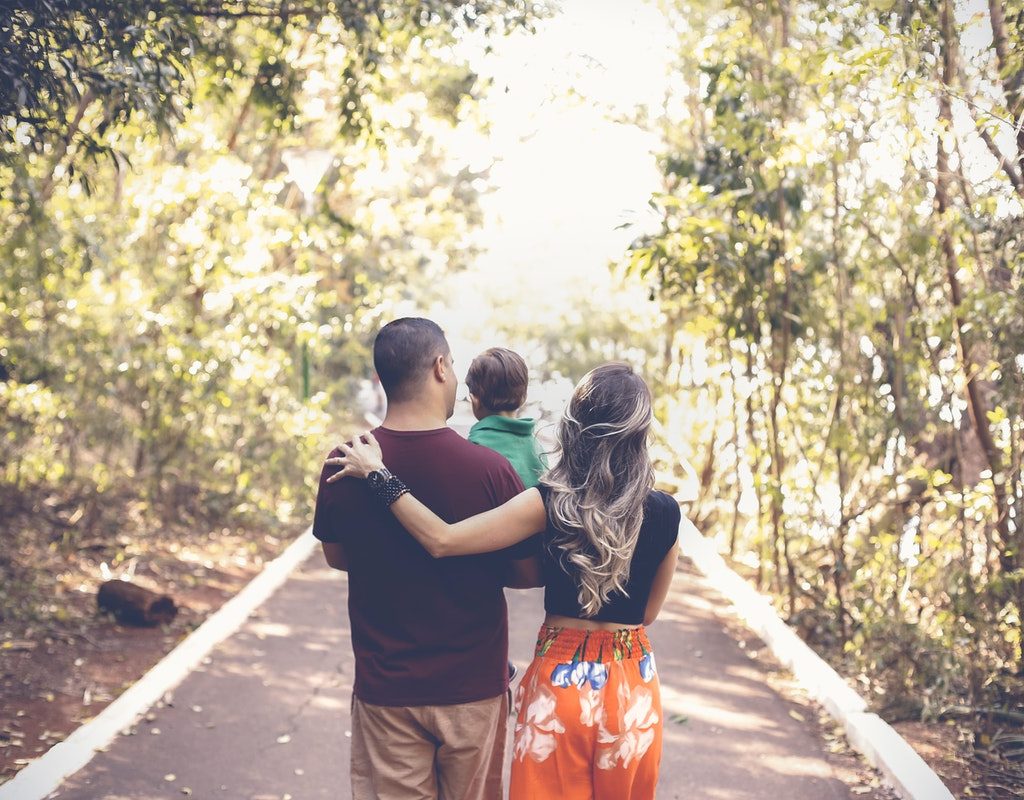 Parents walking down a scenic street holding their child.