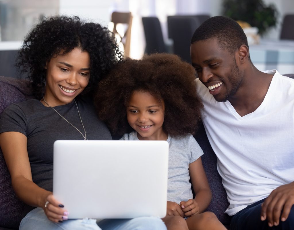 A family gathered around the computer booking a trip