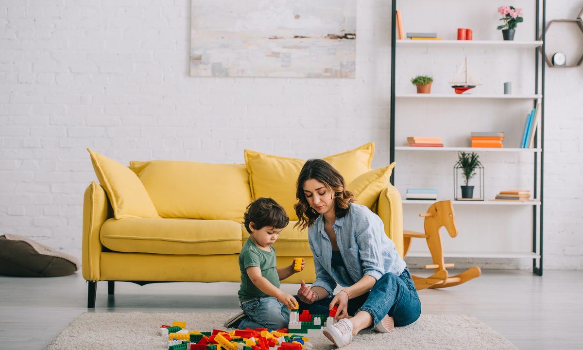 A mom and toddler playing a game in the living room.